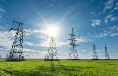 high voltage lines and pylons and a green agricultural landscape on a sunny day. association of agriculture and industry in one photo. beautiful spring landscape of the european plain.