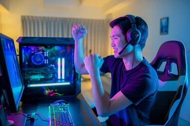 young asian handsome pro gamer feel excited while playing in online cyber sport game at home