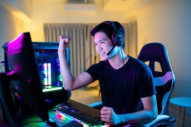 young asian handsome pro gamer feel excited while playing in online cyber sport game at home