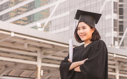 close up of graduate student holding a diploma and looking to the sky, education concept.