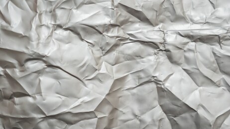 abstract aluminum folded shiny metal silver foil crumpled texture background.
top view.