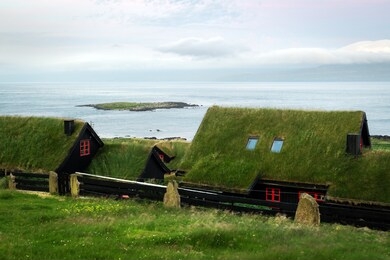 foggy morning view of a house with typical turf-top grass roof and blue cloudy sky in the velbastadur village on streymoy island, faroe islands, denmark. landscape photography