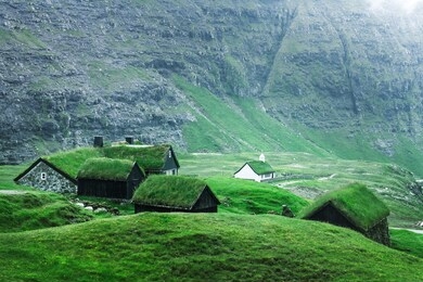 summer view of traditional turf-top church saksunar kirkja in saksun village. beauty landscape with grassy houses and high mountains. streymoy island, faroe islands, denmark.