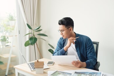 portrait of a smiling young businessman working on blueprints at the office