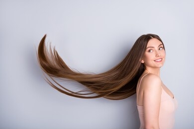 profile photo of attractive model lady look demonstrate ideal neat long healthy hairstyle flying on air after lamination procedure wear beige singlet isolated grey color background