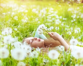 beautiful girl smiling spring dandelion, on the field in green grass blowing dandelion. outdoors. enjoy nature. healthy smiling girl on spring lawn. allergy free concept. 