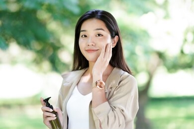 
a young asian woman is using lotion