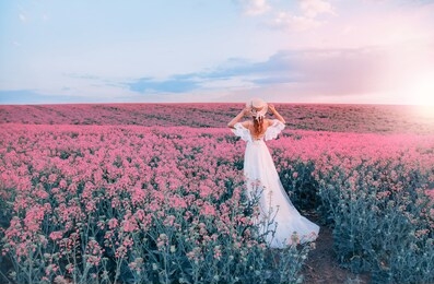 silhouette woman. white long vintage dress. princess medieval lady in historical clothes. straw hat boater flowers. aroma spring nature pink flowering field, blue sky sunset sun light. back rear view