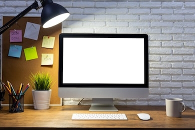 workspace with computer with blank white screen mockup, and office supplies on a wooden desk