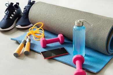 fitness equipment and smartphone on gray floor background. training indoors. home online workout.
