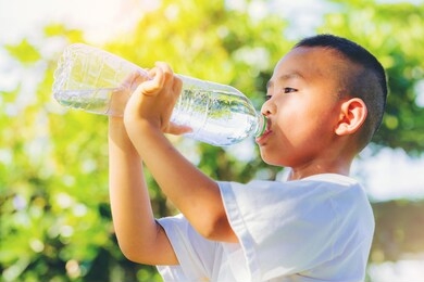 asian little boy drinking pure water from plastic bottle with nature 