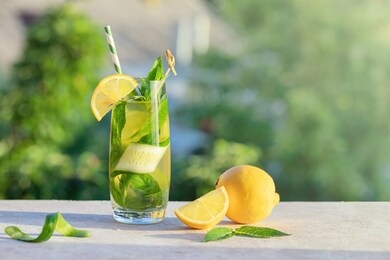 summer concept. lemonade or mojito cocktail with lemon, cucumber and mint, cool refreshing drink or beverage, outdoor.  cold detox water with ice  and paper straw, copy space.