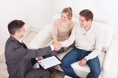 male consultant shaking hand with young couple at home