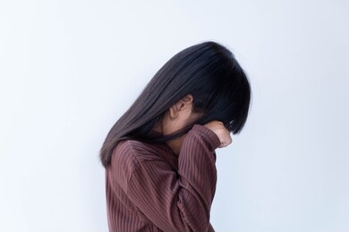 asian girl crying with her hands on her face isolated on a white background.