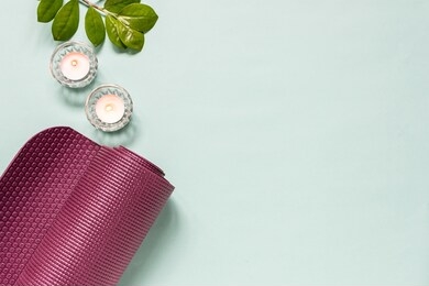 yoga studio banner template with mat and candles on light turquoise background. yoga practice at home concept.