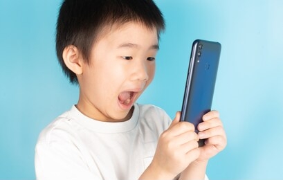 asian children are holding mobile phones by searching for knowledge from online mediaon the internet to improve knowledge. ability in various fields including for fun and entertainment.