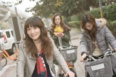 young asian woman riding bicycle with friends in city, taipei, taiwan.