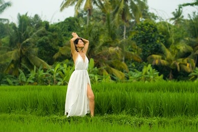 body and mind connection with nature - happy and beautiful asian japanese woman doing yoga and meditation exercise outdoors at idyllic green rice field enjoying tropical summer holidays