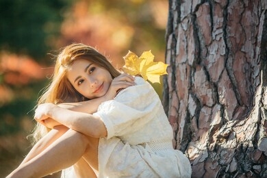 beautiful asian woman with autumn leaves, flower and fall yellow leaves background at hagley park, christchruch, new zealand.