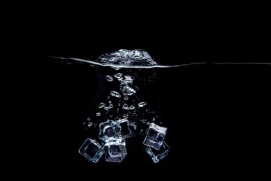 the ice cubes fell into the water, causing spur and bubbles spread in the black background.