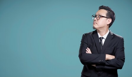 asian businessman wearing suit looking at left isolated on blue background
