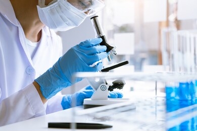 medical research asian scientist working with microscope doing research making scientific experiment, works in a bright modern laboratory