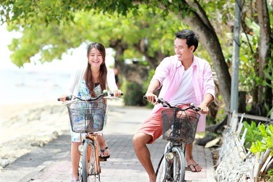 happy asian young couple riding bicycle laughing together