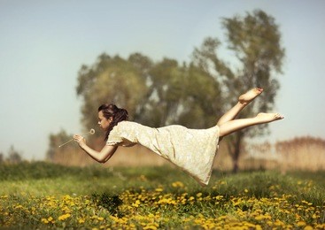 girl in pajamas night flying over the field and smelling dandelions.