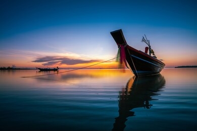 silhouette of sunset time with fishing long tail boats (traditional boats) on the sea at wok tum beach phangan island,thailand