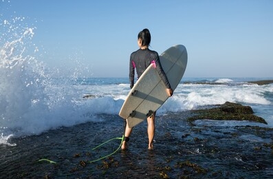 woman surfer with surfboard going to surf on seaside