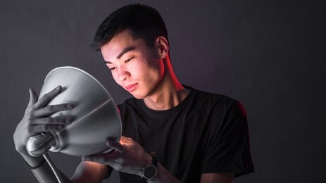 guy of asian appearance holds a lamp in his hands, looks at the light as his hatching