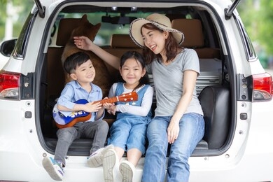 mother and his daughter together with shiba inu dog are sitting on car trunk in the nature. they are sing and smiling. 