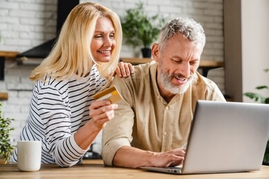 happy couple using credit card for shopping online using laptop