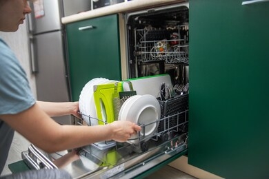 a woman takes clean dishes from the built-in dishwasher inside. home appliances. smart kitchen. appliances.helping a housewife.house cleaning.