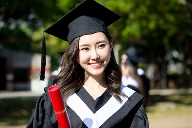 happy female graduate student holding diploma in her hand and smile