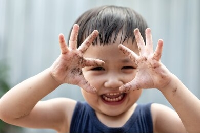 happy asian children playing outside with dirty hands