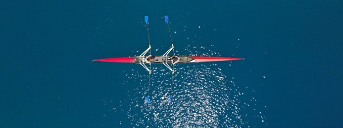 aerial drone top ultra wide panoramic view of sport canoe rowing synchronous female athletes competing in deep blue sea