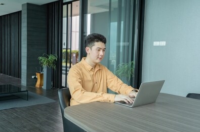 portrait of happy smiling young business asian, chinese man person using laptop notebook computer, working online in meeting room at home in technology device concept. lifestyle