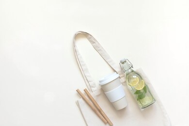 cotton bag, thermos, glass bottle with lemon water and melissa bamboo tubes. let's go shopping. ecological, natural materials. the concept of zero waste. the view from the top.