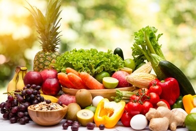 assortment of fresh vegetables and fruits with vitamins c from bananas, kiwi, grapes, raspberries, blueberries, and blackberries, good for the body and diet food on the table in nature background.
