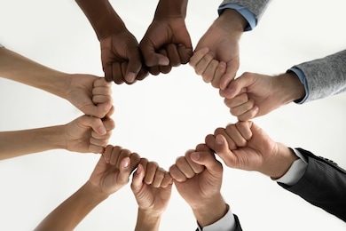 close up bottom view diverse employees team holding fists in circle, expressing unity and power in teamwork, multiethnic business people engaged in team building activity at briefing