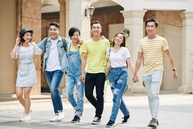group of happy young asian people walking in the street on sunny day