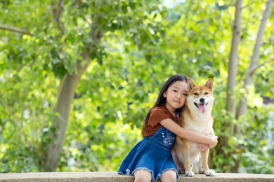 happy girl and dog shiba inu are enjoying playing in a sunny summer garden.