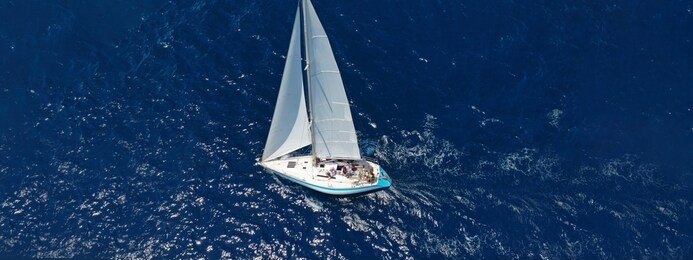 aerial drone ultra wide photo of beautiful sail boat with white sails  sailing open ocean deep blue sea