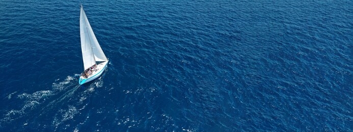 aerial drone ultra wide photo of beautiful sail boat with white sails  sailing open ocean deep blue sea