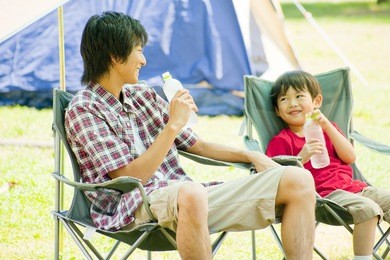 japanese father and son talking while sitting in a chair at campsite