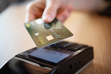 close up hand of woman paying bill with credit card by contactless. hand make payment with credit card with nfc technology on terminal device. mobile payment at coffee shop with card reader machine.