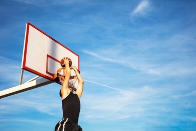 young man jumping and making a fantastic slam dunk playing streetball, basketball. urban authentic.