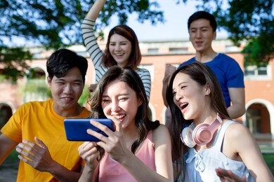 happy young asian teenagers watch ball game on smartphone and they feel very excited