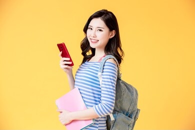 asian female student use smart phone with book
